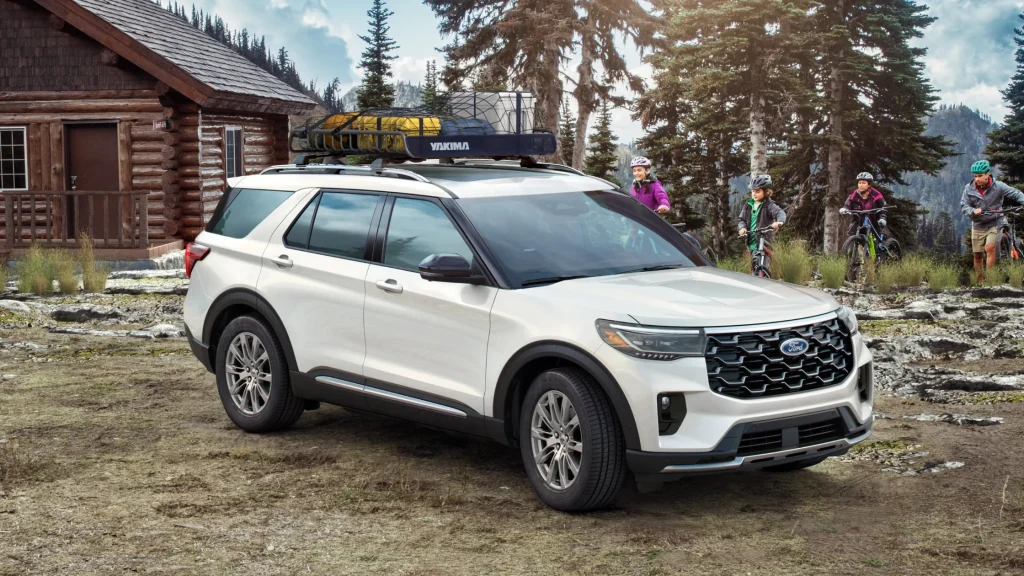 2025 Ford Explorer® in white parked outside a log cabin with a family preparing for biking