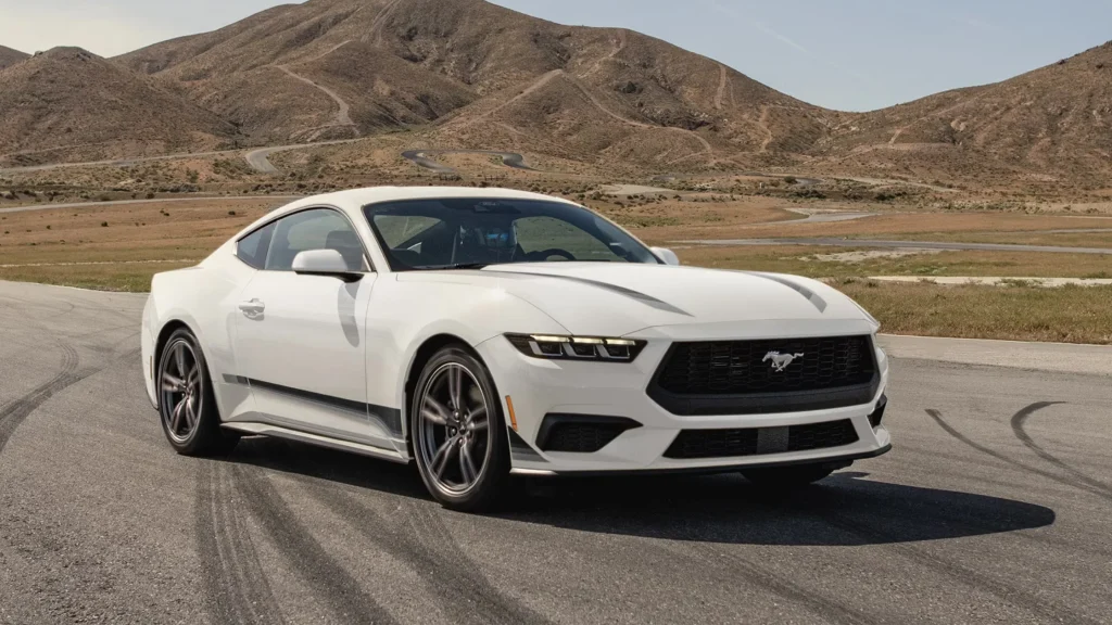 White 2025 Mustang® coupe parked on track with skid marks and scenic hills in the back.