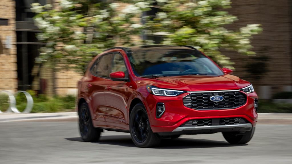 2025 Ford Escape® ST-Line Hybrid in motion with bold red exterior and sporty front grille styling.