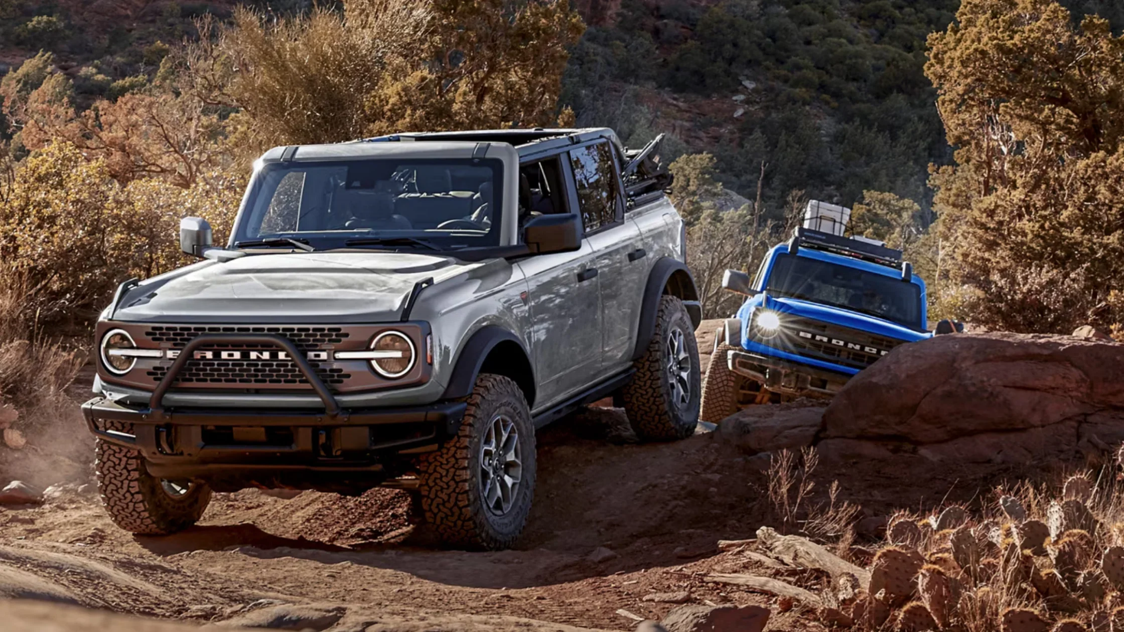 Gray 2025 Bronco® SUV leading on rocky trail with blue Bronco® following behind.