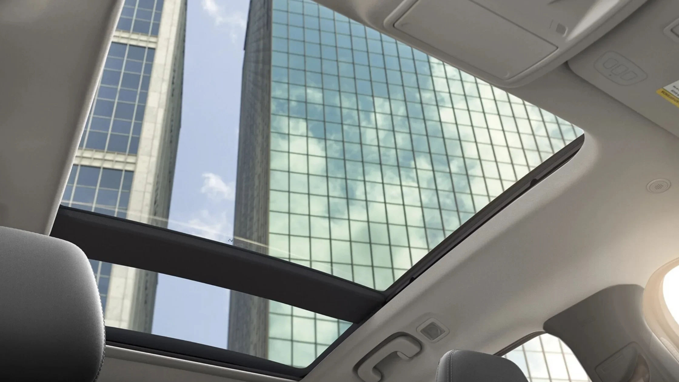 2025 Escape® panoramic sunroof view looking up at tall city skyscrapers against blue sky.