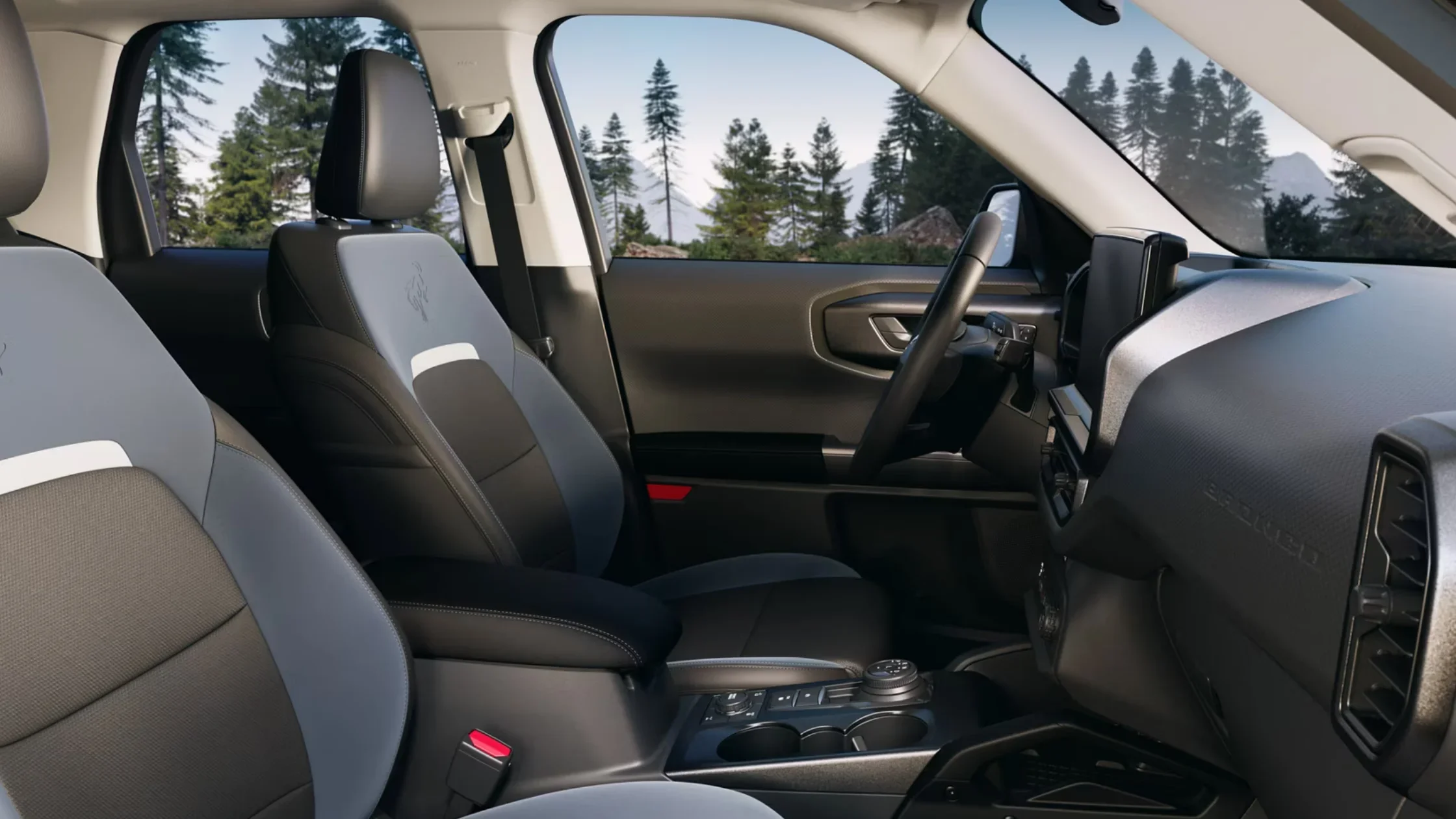 Front seats and cabin layout of 2025 Ford Bronco Sport with forest view background.