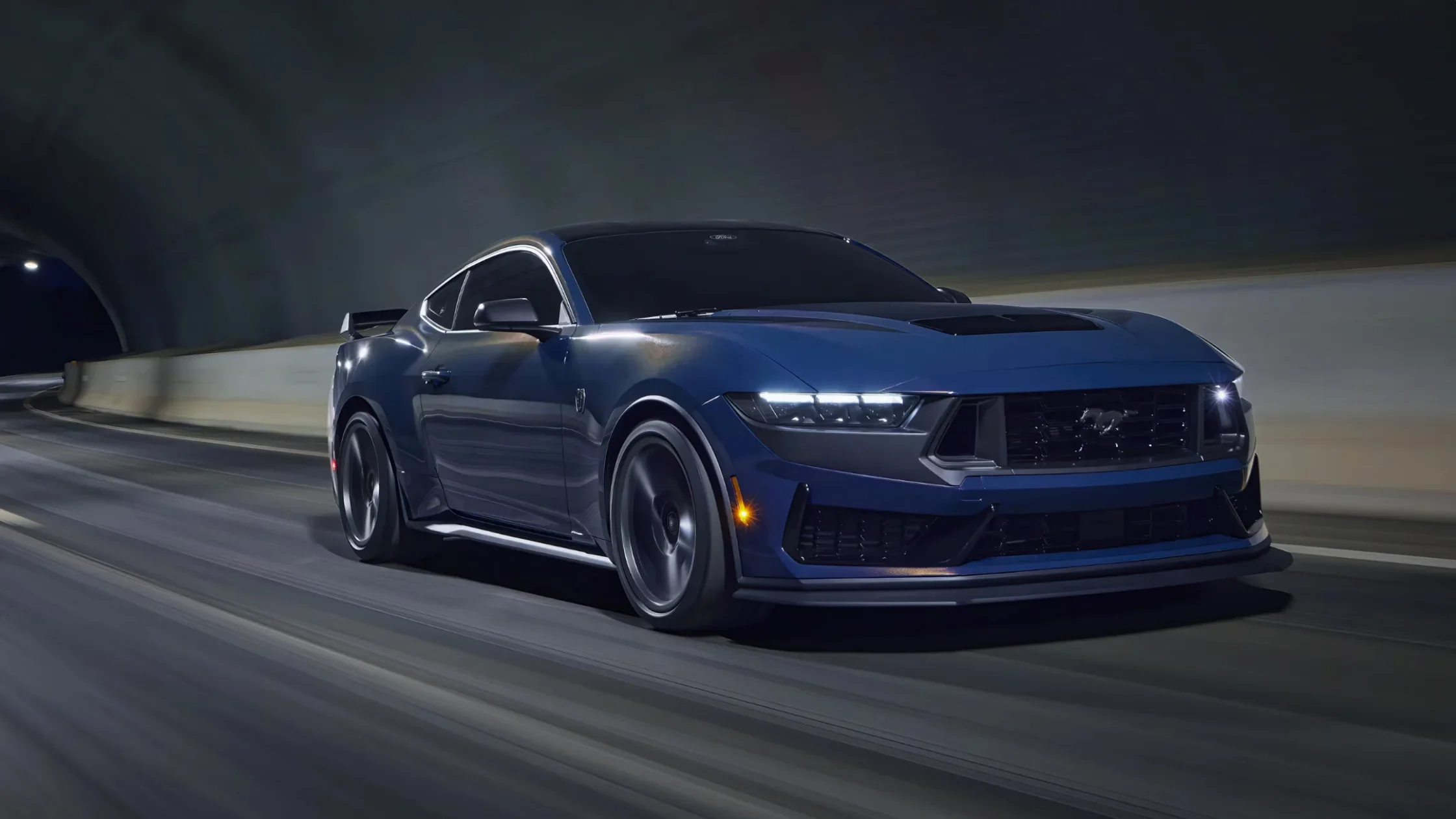 Blue 2025 Mustang® coupe speeding through tunnel with LED headlights on.