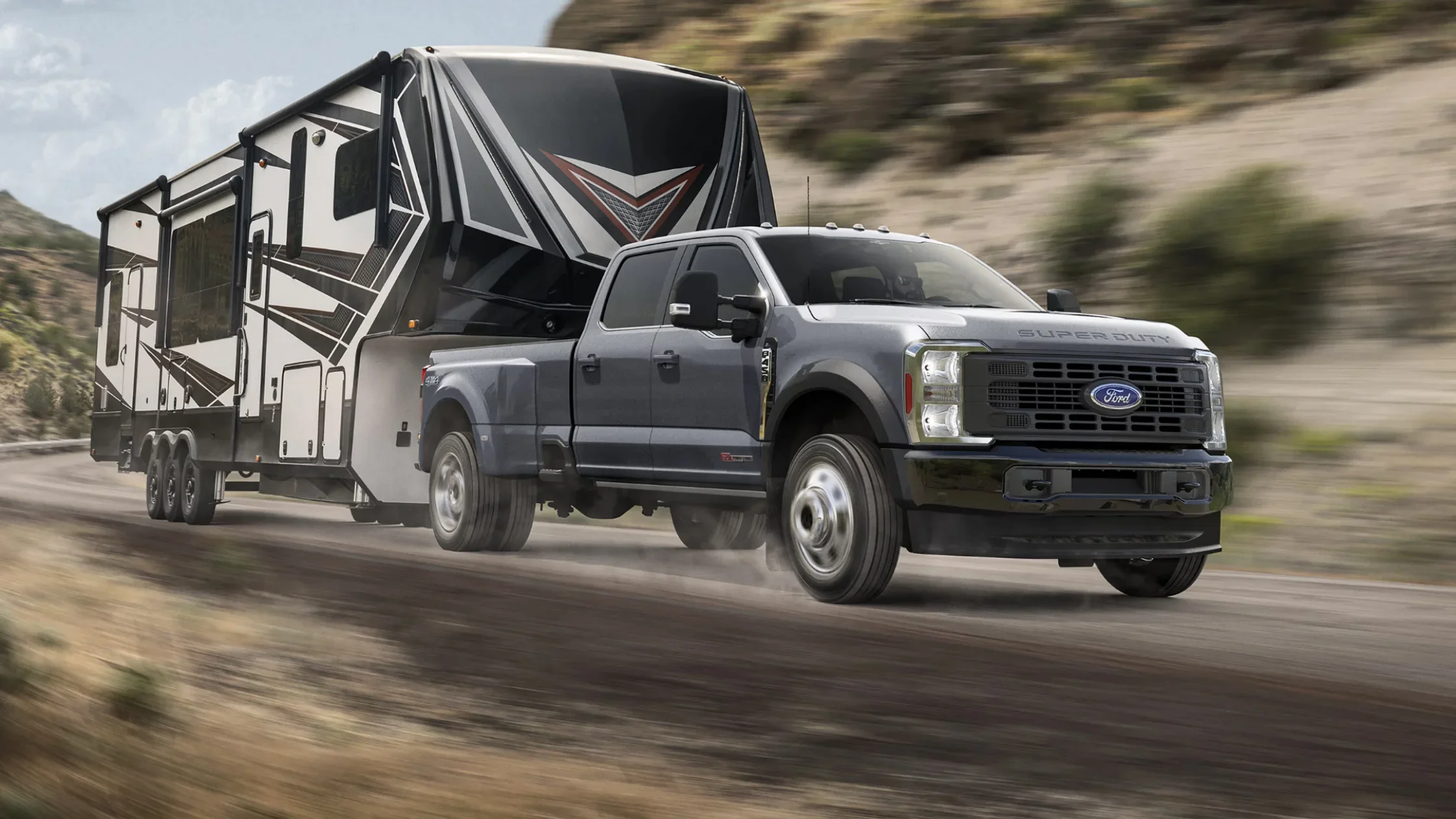 Gray 2025 Super Duty® towing large fifth-wheel trailer on open road.