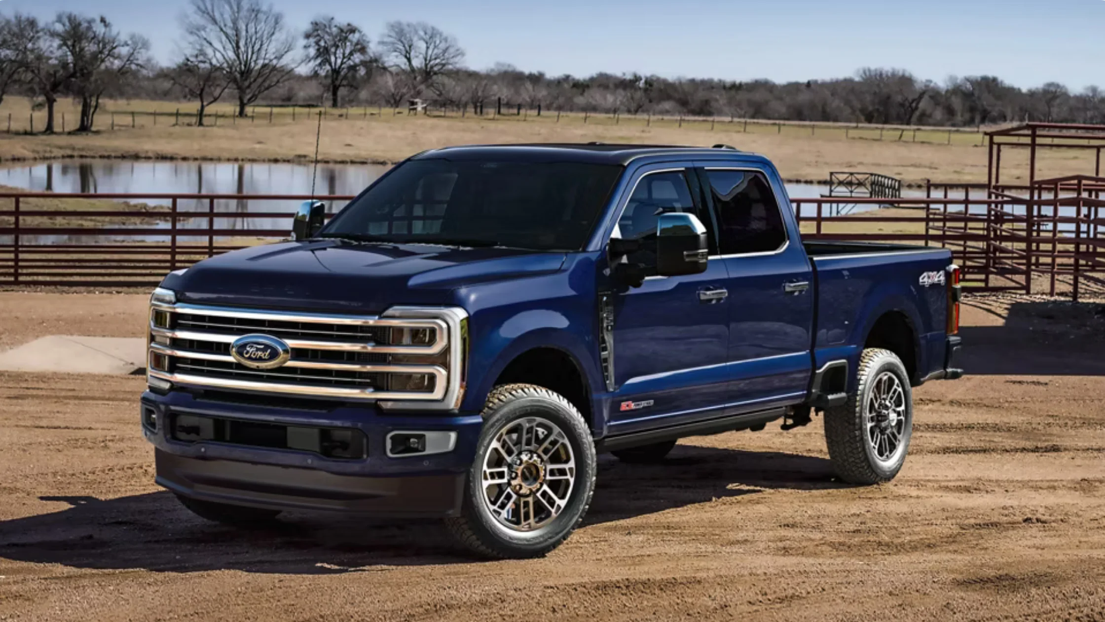 Exterior view of the 2025 Ford Super Duty® F-350® in blue parked near a ranch with chrome grille and bold stance.